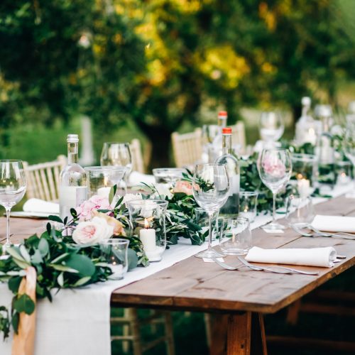 Floral garland of eucalyptus and pink flowers lies on the table for wedding reception. Italian dinner